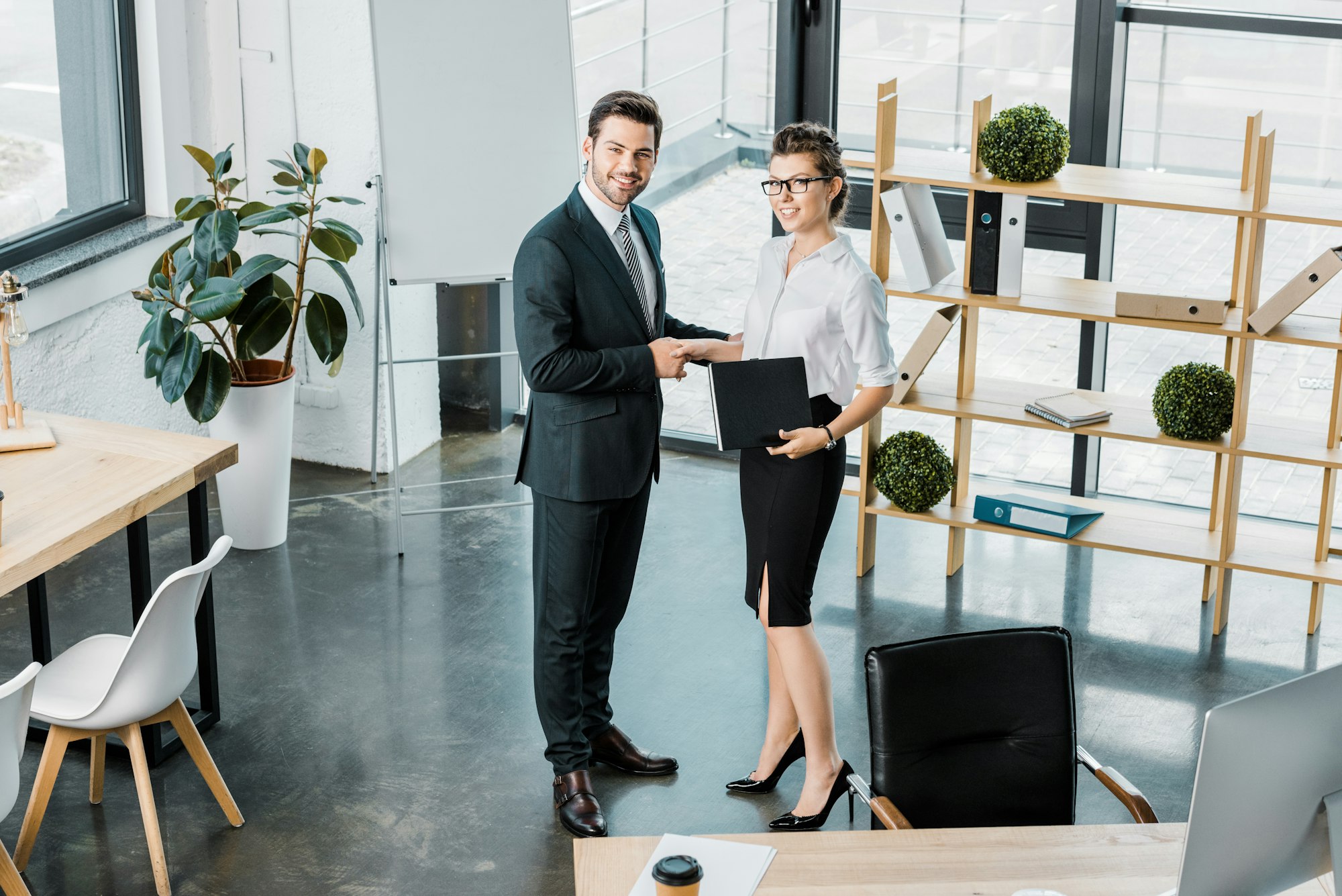 high angle view of smiling business colleagues shaking hands in office